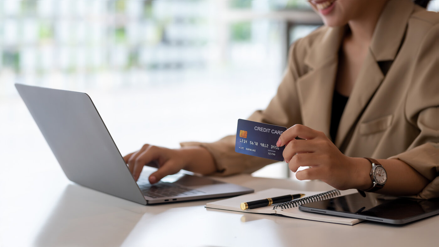 A person holding a credit card and using a laptop to make a secure online payment